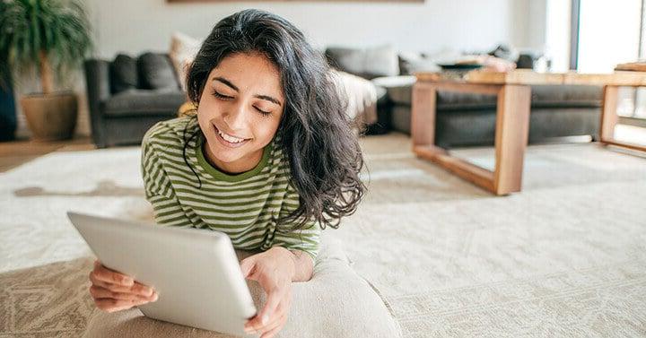 Girl reading a tablet while laying on the floor - Connections Academy