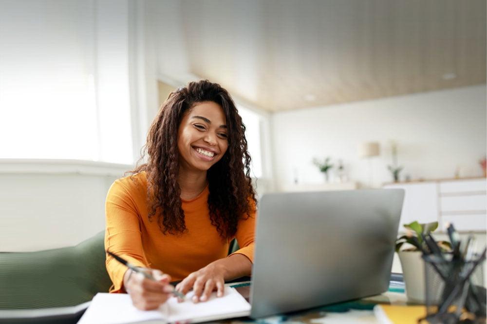 Online school student in Louisiana on her laptop and writing in a notebook